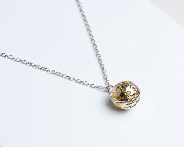 Silver ball pendant with textured surface and gold