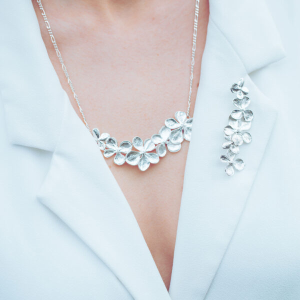 hydrangea silver necklace on a chain plus a brooch worn by a model